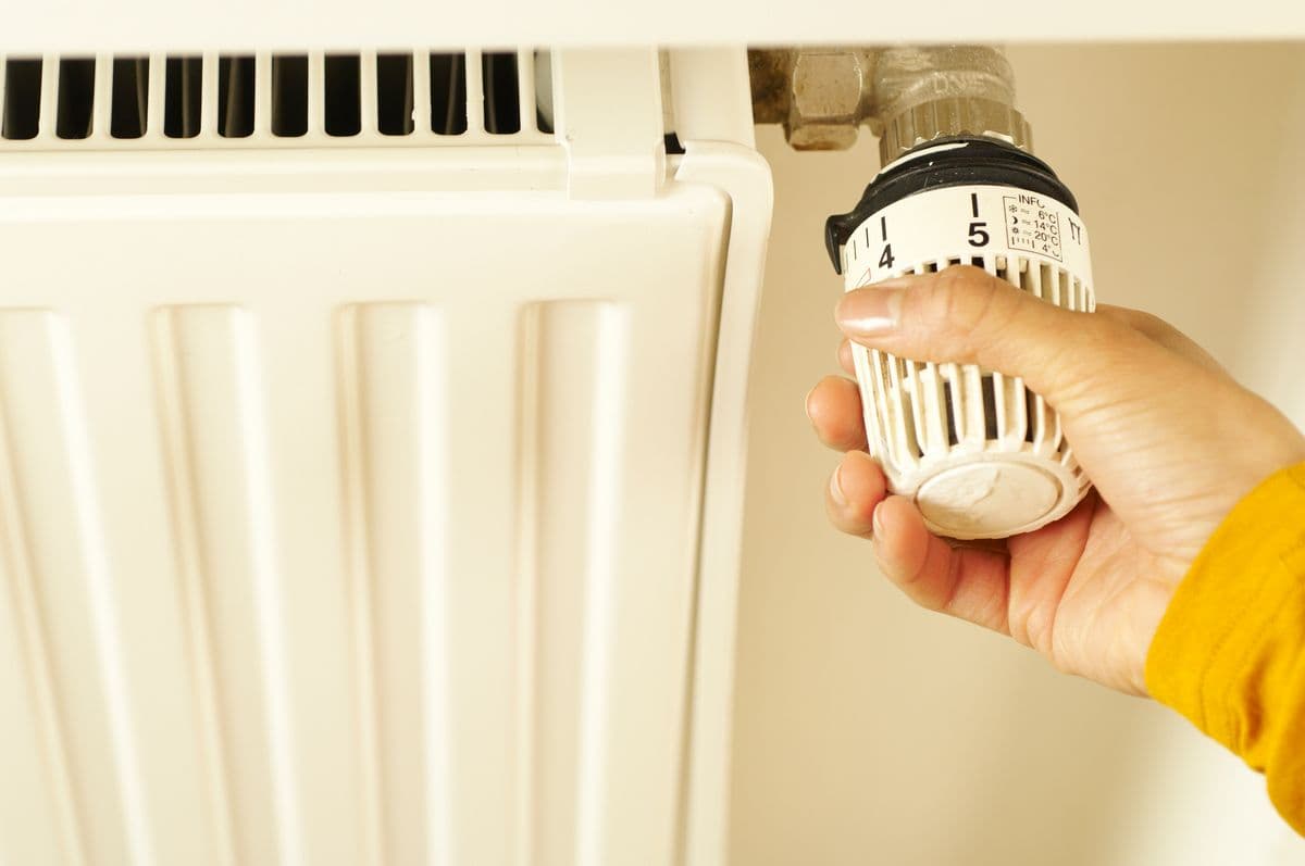 Hand adjusting radiator thermostat valve — a simple check when your boiler stopped working but radiators are cold