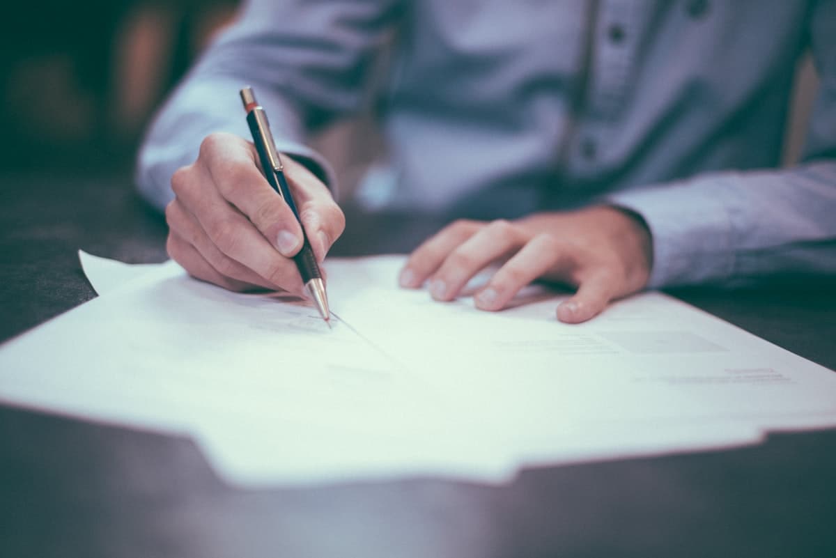 Insurance policy documents on a desk — car insurance schedule contains the policy number, renewal date, and claims line